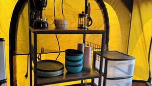 Un coin cuisine équipé d’une machine à café, d’une cafetière à piston et de récipients de rangement.
