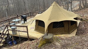 Une tente dotée d’une terrasse en bois, d’un barbecue et d’une table.