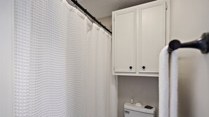 A bathroom with a shower curtain, a toilet, and a towel rack.