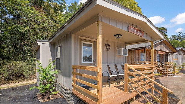 A wooden cabin with a porch, a sign reading "Kay S Hook", and outdoor seating.