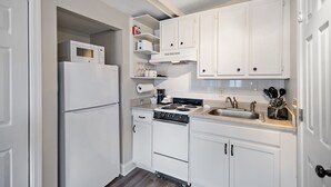A kitchen with white cabinets, a refrigerator, a microwave, a stove, and a sink.