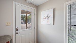 A door with a window, a framed artwork on the wall, and a couch in the foreground.