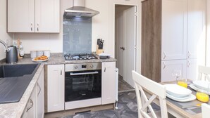 Une cuisine compacte équipée d’une cuisinière, d’un four et de meubles de rangement modernes.