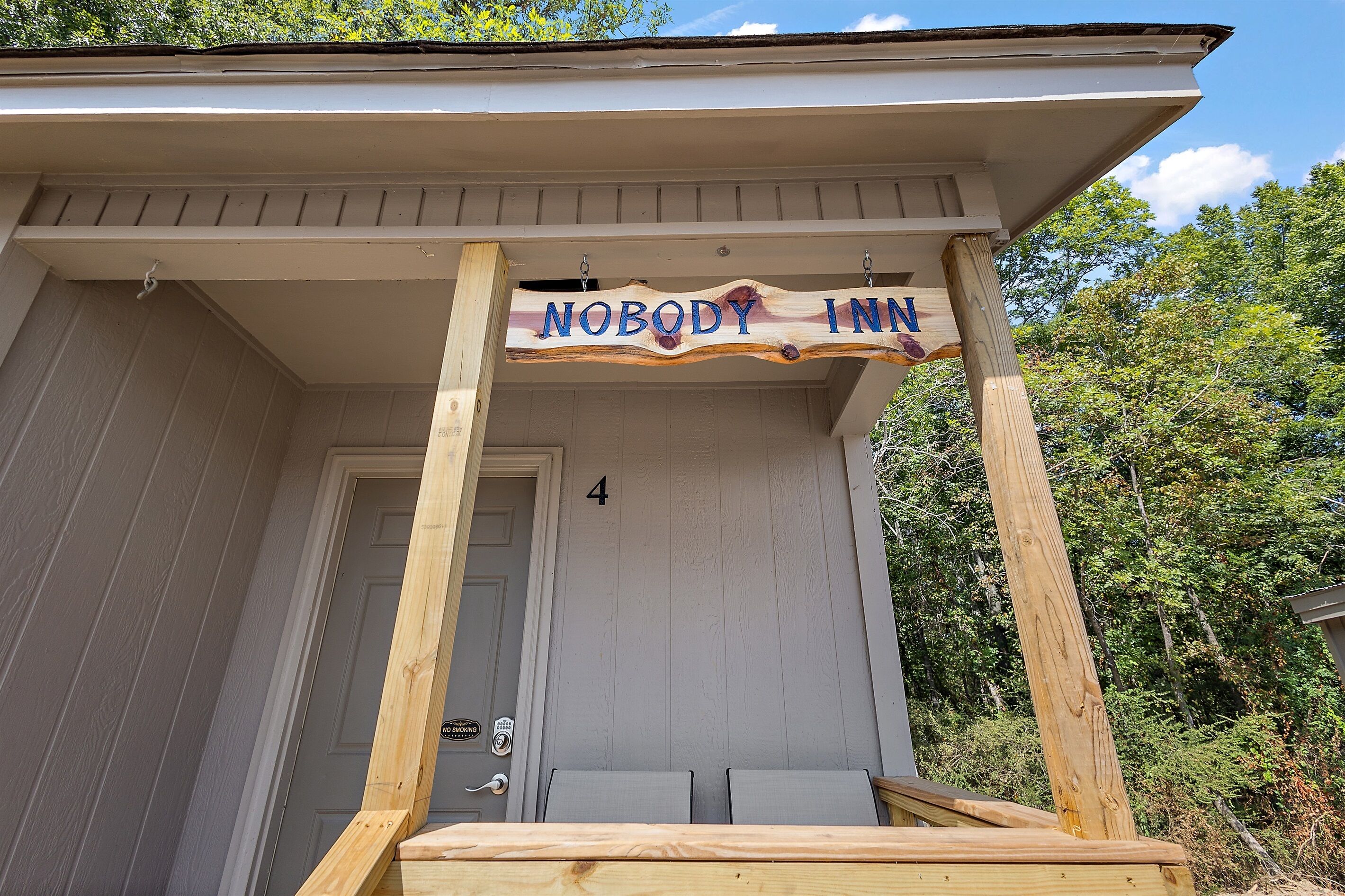 Una estructura de madera con un letrero que dice "NOBODY INN" y el número 4 en la puerta.