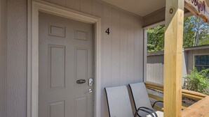 A door with a "No Smoking" sign, a number "4" on the wall, and two chairs outside. - Cottage 4 - Nobody Inn (Ridgeland)