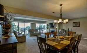 Relax in this inviting living room with a large dining table, fireplace, and TV.