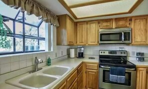 Enjoy cooking in this well-equipped kitchen with a double sink, coffee maker, and stove.