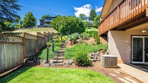 Een achtertuin met houten omheining, stenen trap en een kleine tuin.