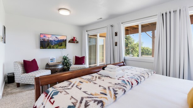 Een slaapkamer met een groot bed, een stoel, een tafeltje en een schilderij aan de muur.