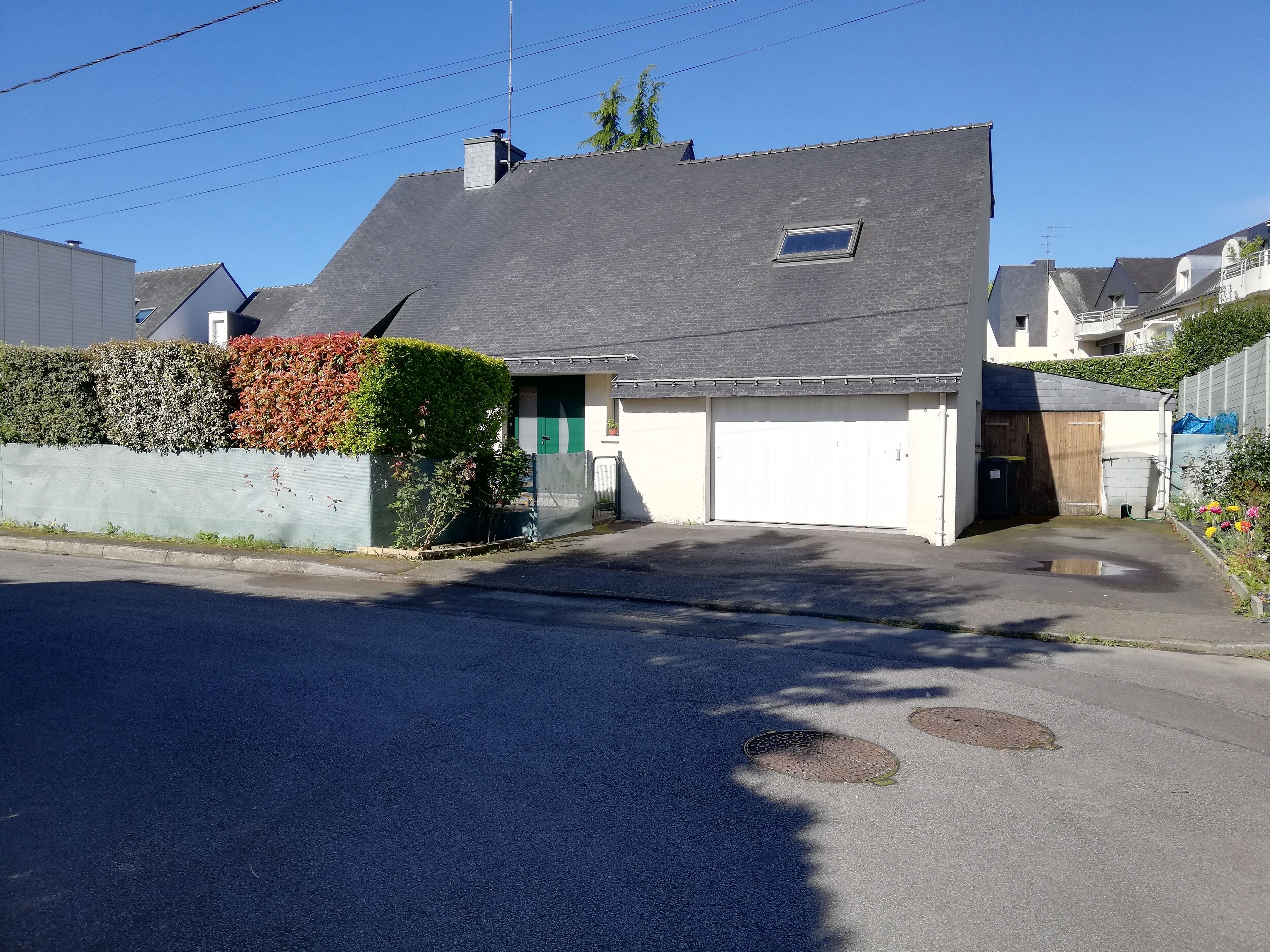 Une maison d’habitation avec un garage, une petite fenêtre et un ciel dégagé.