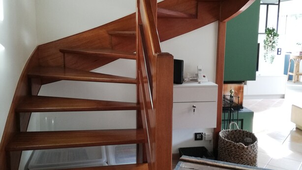 A wooden spiral staircase with a white wall and a green accent wall in the background. - House in quiet, comfortable neighbourhood, close to town center and shops (Vannes)