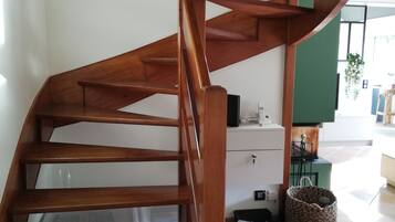 Een houten spiraaltrap met een witte muur en een groene accentmuur op de achtergrond.