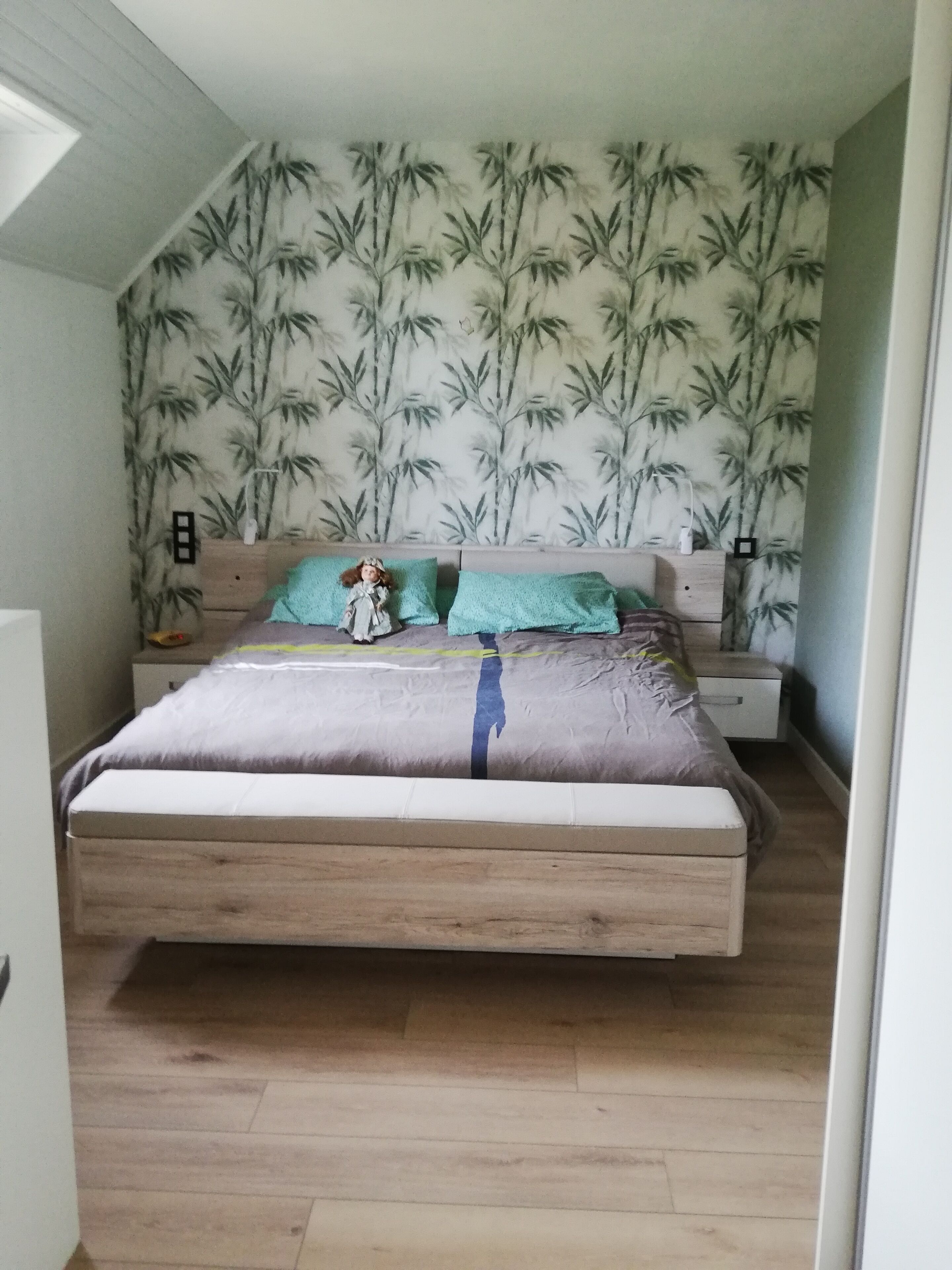 Een slaapkamer met een bed, nachtkastje en een muur met bamboepatroon.