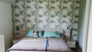 A bedroom with a bed, a nightstand, and a wall with a bamboo pattern. - House in quiet, comfortable neighbourhood, close to town center and shops (Vannes)