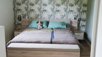 Een slaapkamer met een bed, nachtkastje en een muur met bamboepatroon.