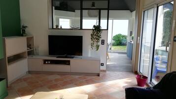 Een moderne woonkamer met een flatscreen televisie, een salontafel en een schuifpui die leidt naar een balkon.