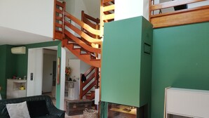 A living room with a green wall, a wooden staircase, a fireplace, and a sofa. - House in quiet, comfortable neighbourhood, close to town center and shops (Vannes)