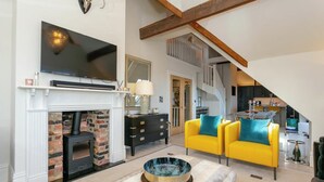 A spacious living room with a fireplace, a television mounted above it, and a yellow sofa with teal cushions. - Executive 3 bedroom Penthouse apartment, 2 bath and Mezzanine (Harrogate)