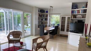 A modern living room with a dining area, a bookshelf, and a TV.