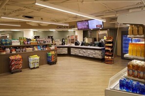 Interior de una tienda de comestibles con una barra de autoservicio para embutidos, vitrinas refrigeradas y una gran variedad de productos envasados.