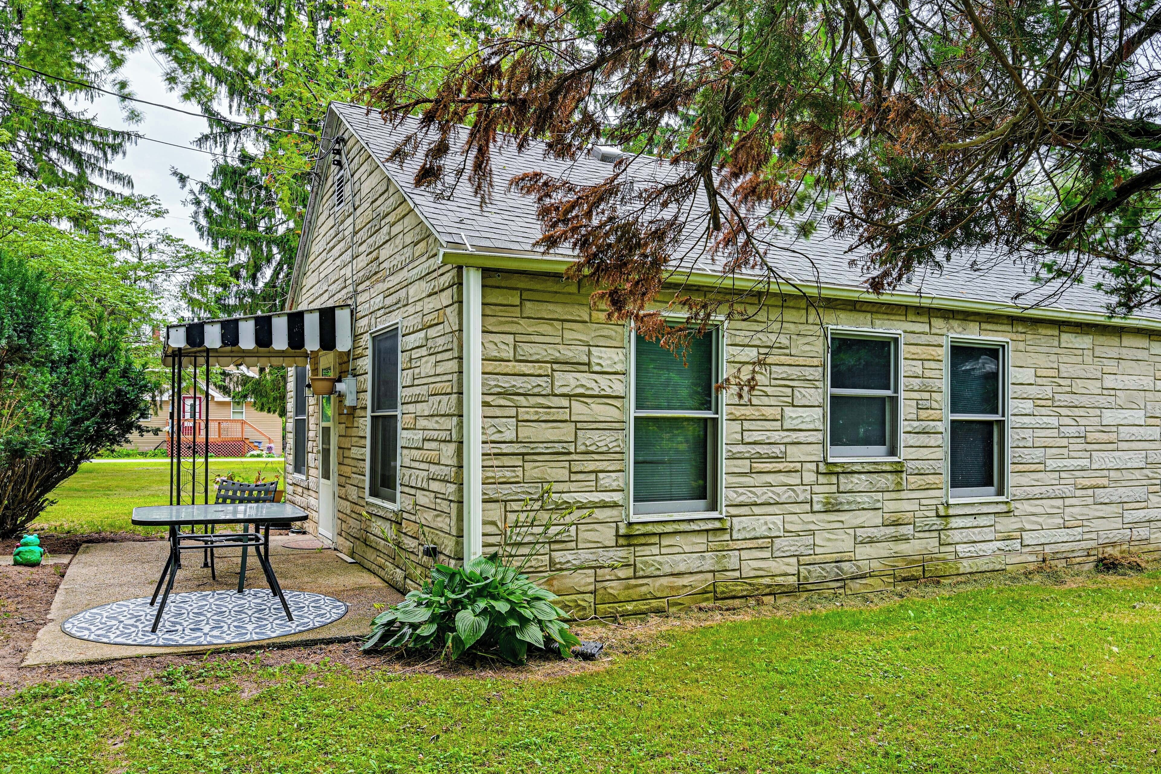 Une maison en pierre avec un patio couvert et un petit jardin.