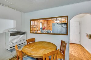 Um quarto com uma mesa redonda de madeira, duas cadeiras, um aparelho de ar condicionado branco e um armário de madeira com espelho.