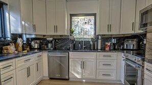 A modern kitchen with white cabinets, stainless steel appliances, and a large window. - Tranquil Modern Farmhouse (Waldorf)