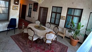 A dining area with a table set for four, surrounded by chairs, a chandelier, and a potted plant. - Sılto's Butik Otel (Mardin)