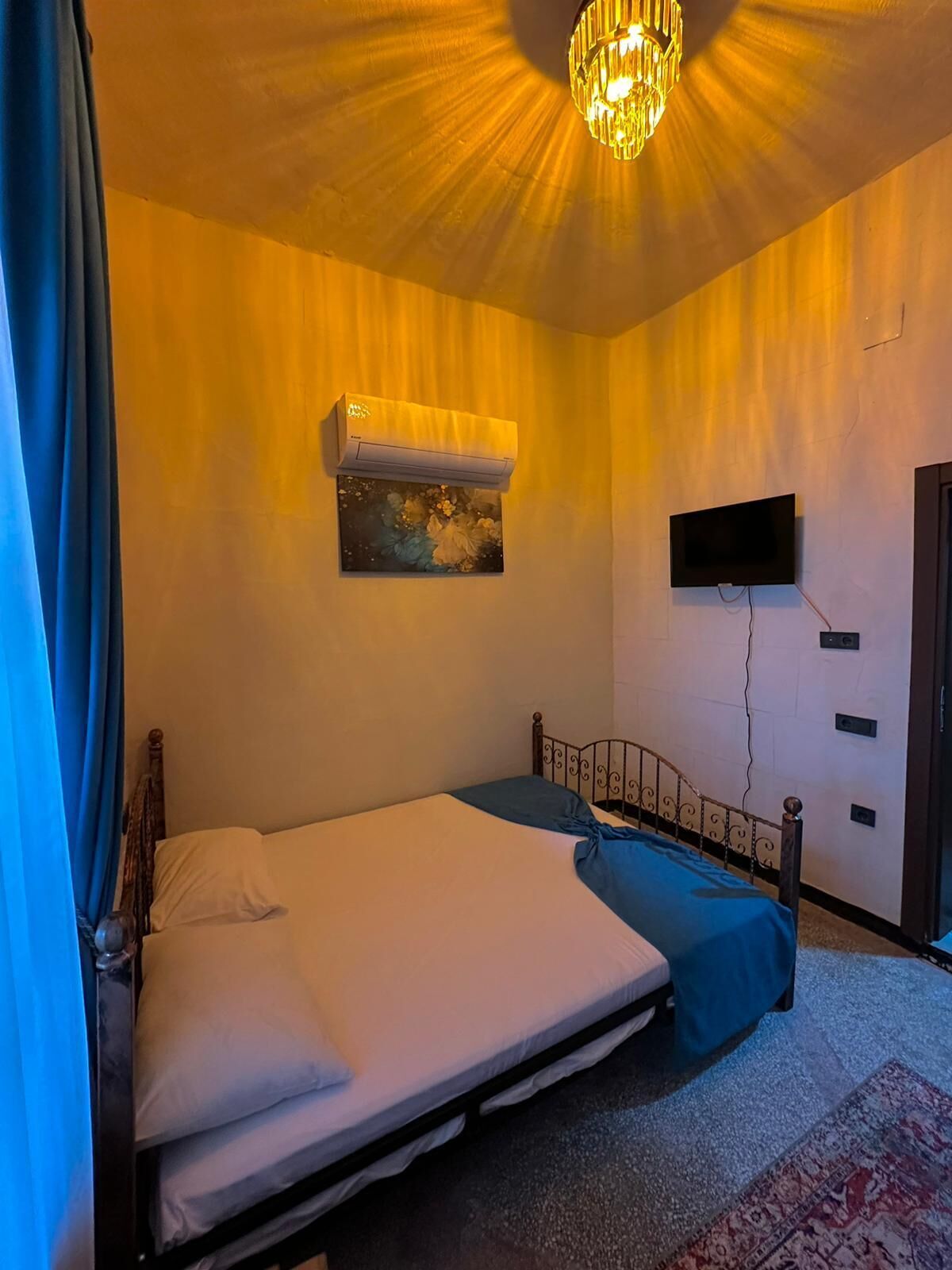 Un dormitorio con cama, televisor montado y equipo de aire acondicionado.