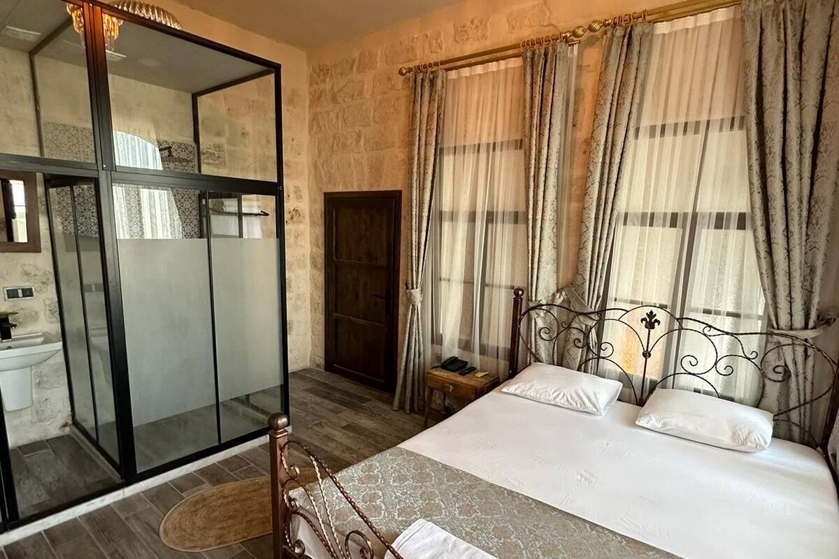 Ein Schlafzimmer mit einem großen Bett, einer Kristallleuchter, einem Spiegel und Blick ins Freie.