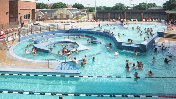 A large outdoor swimming pool with multiple lanes and a separate shallow area for children.