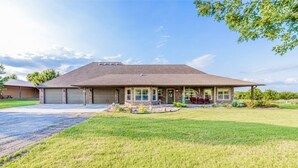 A two-story house with a front garage, a well-maintained lawn, and a clear sky.