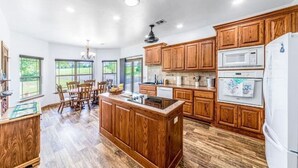 A spacious kitchen with wooden cabinets, a central island, and a refrigerator.