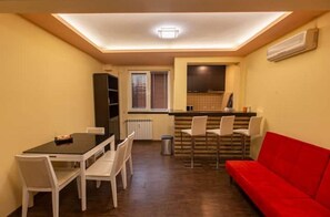 Espaço compacto com área de jantar, cozinha compacta e sofá vermelho.