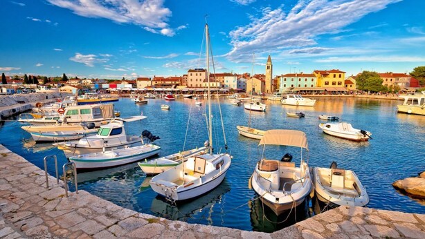 A marina with various boats docked, a prominent tower in the background, and a stone waterfront. - Ul. Dinka Trinajstića 10 (Pazin)