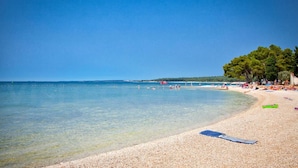 A beach with clear water, pebbly shore, and trees. - Ul. Dinka Trinajstića 10 (Pazin)