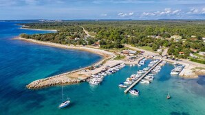 An aerial view of a coastal marina with boats docked, a pier extending into the water, and surrounding greenery. - Ul. Dinka Trinajstića 10 (Pazin)