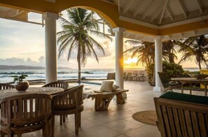 Guests can enjoy the ocean view from this outdoor seating area, featuring comfortable tables and chairs.