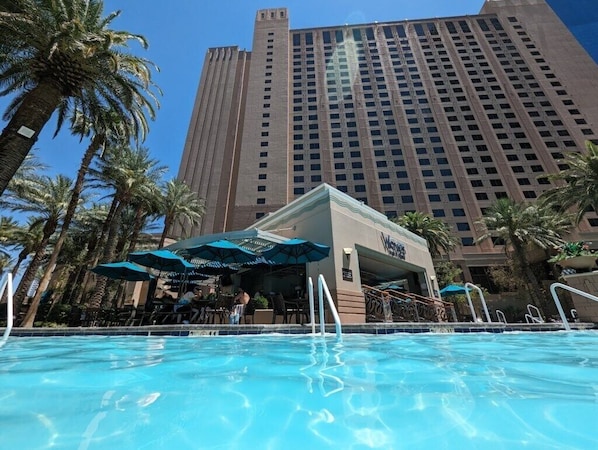 A hotel pool area with a view of a tall building in the background.
