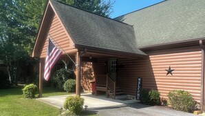 A log cabin-style building with a porch, an American flag, and a 'WELCOME' sign. - Cabin close to Helen and Water (Hiawassee)