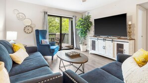 A living room with a sofa, armchair, coffee table, TV, and a balcony with a plant. - Pointe Royale*Autumn Stay*KING Beds* (Branson)