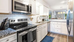 A modern kitchen with white cabinetry, stainless steel appliances, granite countertops, and a blue rug. - Pointe Royale*Autumn Stay*KING Beds* (Branson)