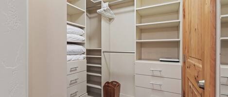 A walk-in closet with open shelves, drawers, and hanging space.