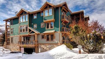 A multi-story lodge with a stone foundation, large windows, and a prominent entrance.
