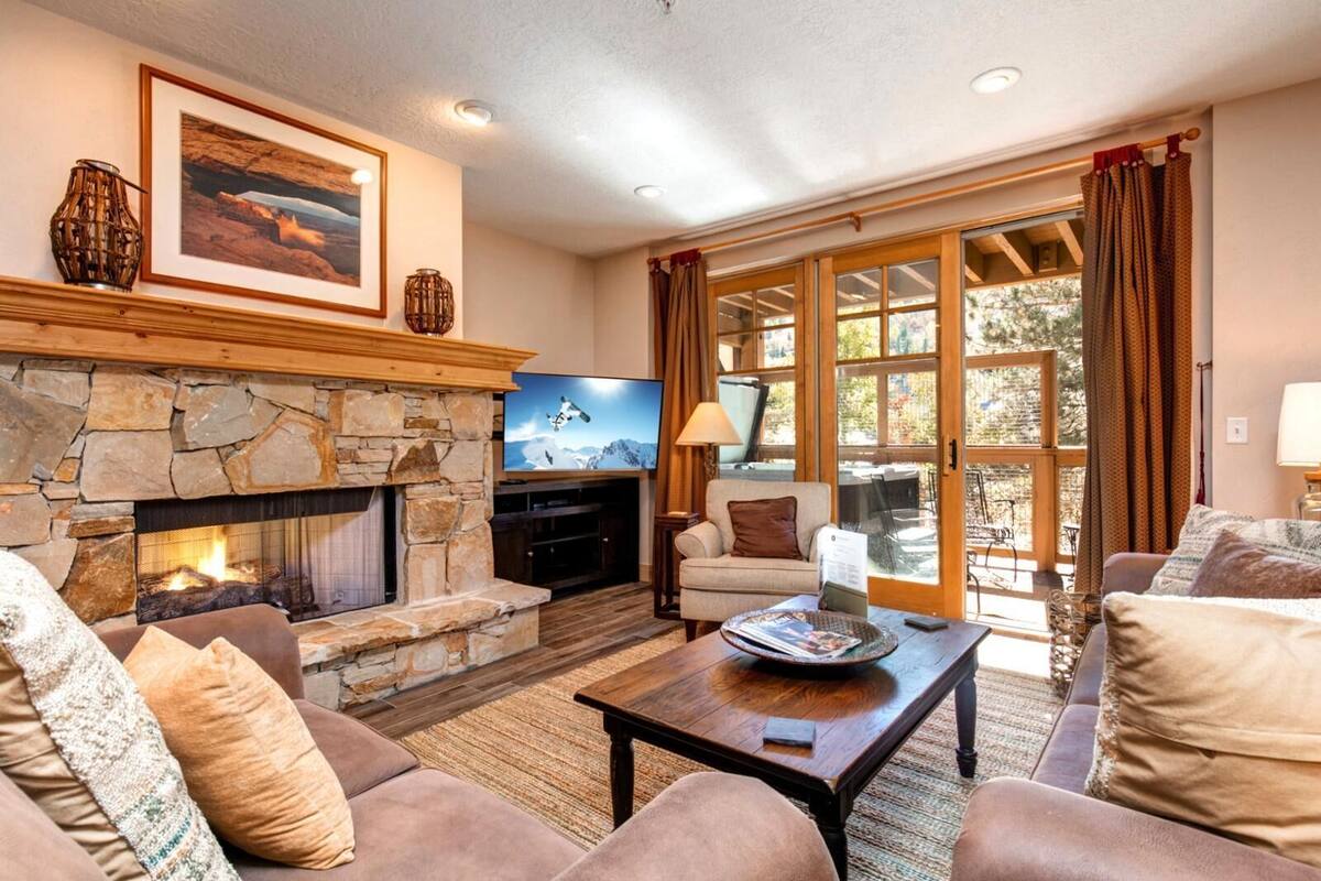 Una sala de estar acogedora con chimenea de piedra, asientos cómodos y un amplio ventanal con vistas al exterior.