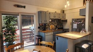 Eine kompakte Küche mit Essbereich, ausgestattet mit einer Schiebeglasdoor zum Außenbereich, einer eingebauten Mikrowelle und einem Kühlschrank mit Fotos.