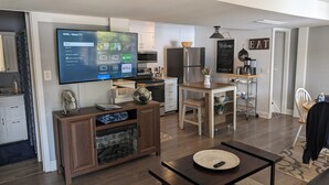A modern kitchen with a flat-screen TV displaying a streaming service interface, a built-in oven, and a coffee station. - Tranqulity and relaxtion destination (Syracuse)
