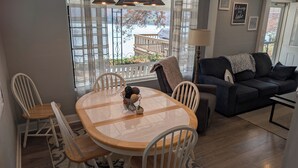 A dining area with a round table and chairs, a sofa, and a view of a deck and water. - Tranqulity and relaxtion destination (Syracuse)