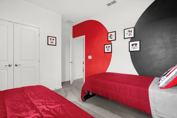 A bedroom with two beds, a large red '1' on the wall, and framed pictures.