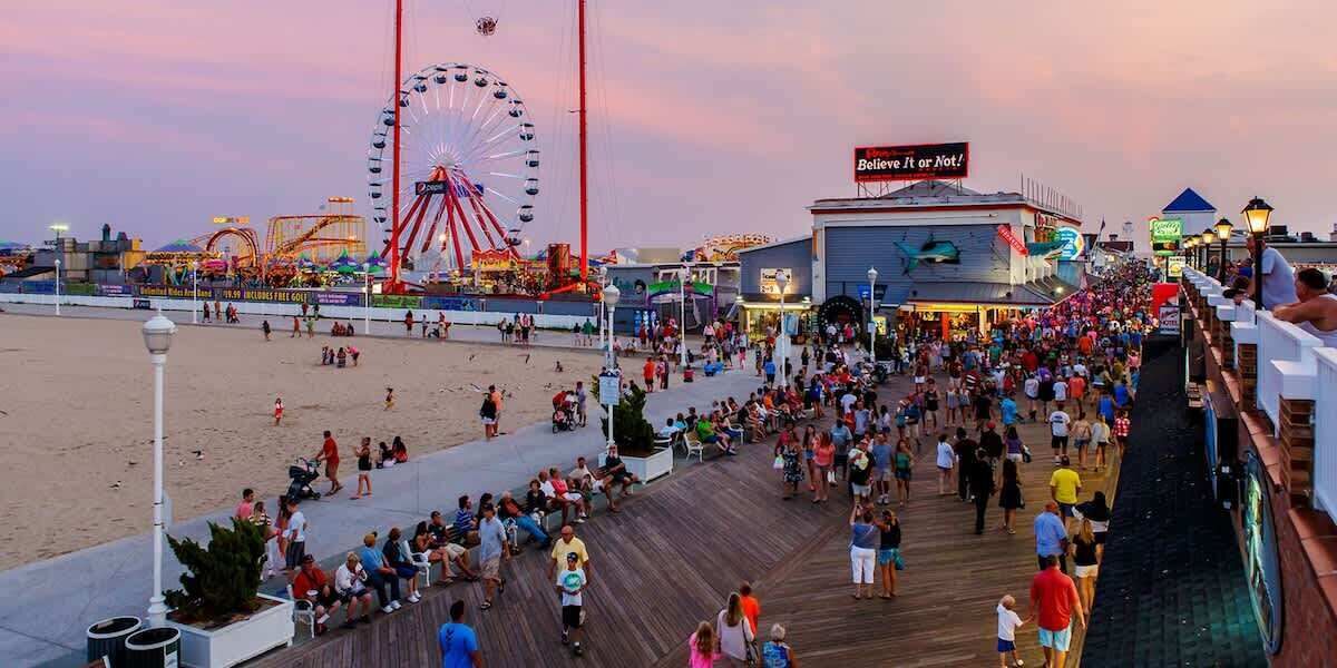 Ein Promenadendeck mit Riesenrad, Strand und einem Gebäude mit Schild.